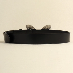 Détail d'une ceinture en cuir noir avec boucle métallique gaufrée en forme papillon