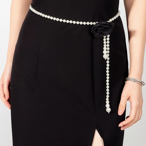 Detailopname van de parel-tailleketting met een decoratieve zwarte stoffen roos aan de zijkant