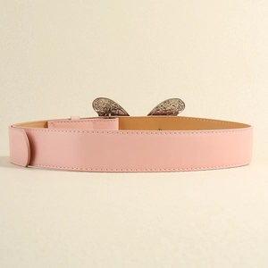 Détail de la ceinture en cuir rose avec boucle en métal sculpté style papillon rétro
