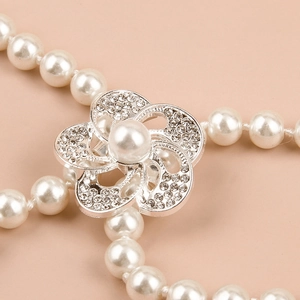 Detailopname van een elegante parelketting riem met een strass bloemenhanger