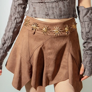 Detail of sunflower metal waist chain and asymmetric brown suede skirt on a model