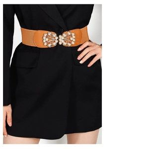 Detail of a brown elastic wide waist belt featuring a gold leaf buckle and pearl accents