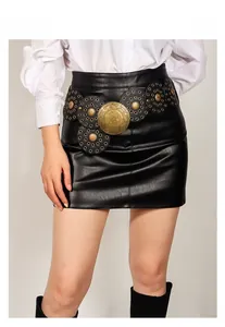 Vue détaillée d'une ceinture western en bronze vintage associée à une mini-jupe en cuir noir
