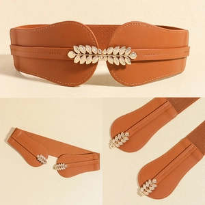 Detail of a brown elastic waist belt with an elegant gold leaf buckle and leather texture