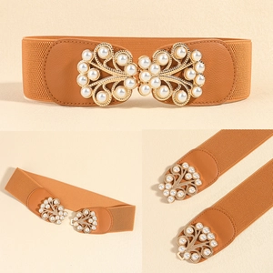 Close-up of caramel elastic belt with golden pearl-studded wing buckle detail