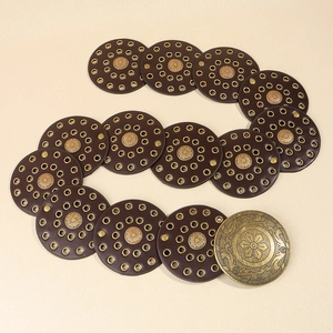 Détail d'une ceinture western vintage avec modules ronds en cuir marron et boucles dorées