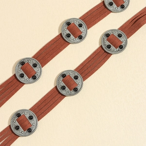 Detailaufnahme des braunen Wildleder-Quastengürtels mit runden silbernen Vintage-Metallnieten