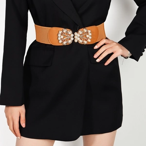 Brown elastic waist belt with gold pearl bow buckle on a black blazer dress