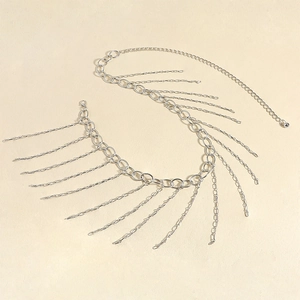 Détail d'une chaîne de corps argentée avec franges métalliques et fermoir mousqueton