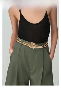 Détail de la ceinture dorée à double couche avec boucle fleur sur une tenue décontractée
