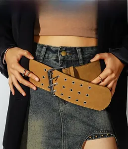 Détail d'une large ceinture en daim marron avec trois rangées d'œillets argentés et boucle