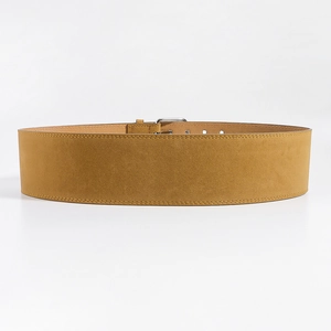Détails de la texture d'une ceinture en daim jaune gingembre avec boucle argentée