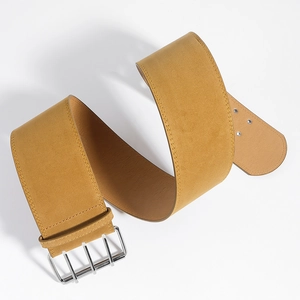 Détail d'une large ceinture en daim jaune moutarde avec boucle argentée à quatre rangs