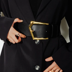 Detailed view of wide black corset belt with a bold gold geometric buckle on a suit