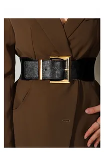 Gros plan d'une large ceinture noire avec boucle dorée rectangulaire sur un manteau brun