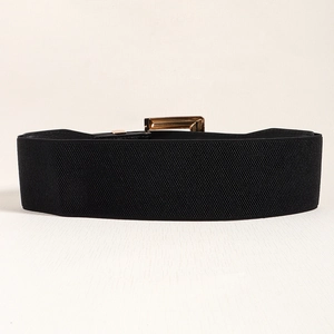 Détail d'une large ceinture élastique noire avec boucle rectangulaire en métal doré