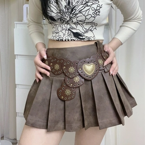 Detail view of Western style belt with baroque metal buckle on brown pleated mini skirt