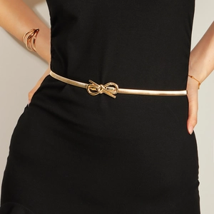 Détail d'une ceinture dorée élastique en métal avec boucle nœud sur robe noire