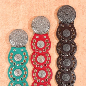 Detail of bohemian leather belts with silver mandala buckles and colorful rivet studs