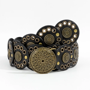 Detailed macro view of vintage bohemian belt with brass mandala buckle and metal studs