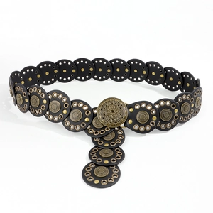 Macro shot of vintage black leather belt with rivets and mandala embossed metal buckle