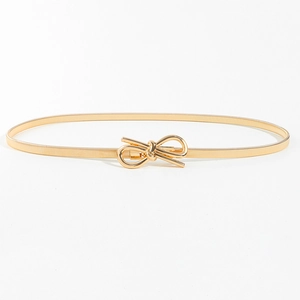 Détail d'une ceinture dorée élastique à ressort avec boucle nœud en métal pour robe