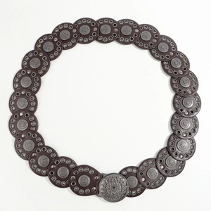 Detailed view of bohemian belt with round brown leather discs and engraved metal buckle