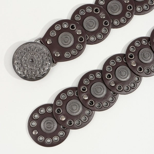 Close-up of bohemian brown belt featuring vintage mandala metal discs and silver rivets