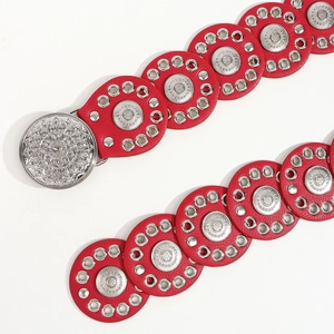 Detail of red boho belt with vintage metal rivets and intricate carved buckle