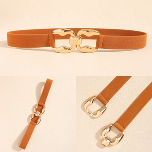 Detail of interlocking gold geometric buckle on a stretchable orange elastic waist belt