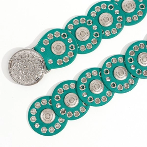 Detail of turquoise leather disc belt with bohemian silver buckle and metal eyelets