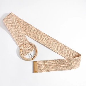 Détail d'une ceinture tressée beige avec une boucle ronde en acrylique marbré