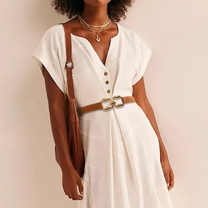 Detail of a brown elastic waist belt with a golden interlocking metal buckle on a white dress