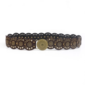 Close-up of vintage bohemian waist belt with embossed sunburst buckle and brass grommets