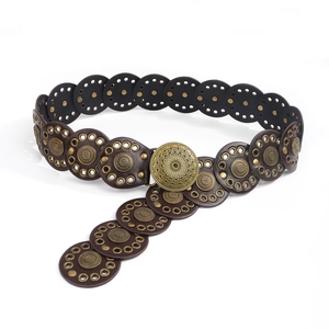 Macro view of vintage Y2K leather belt with bronze rivets and mandala buckle detail