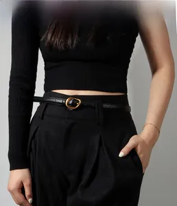 Detail showing slim black leather belt with golden oval buckle on tailored suit trousers