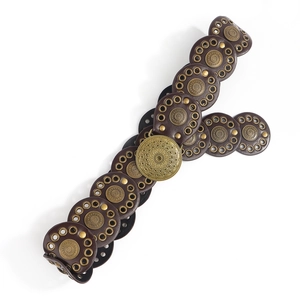 Close-up of vintage brown leather belt with bronze rivets and bohemian embossed buckle