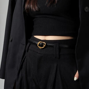 Detail of minimalist black thin leather belt with a vintage gold oval buckle for women