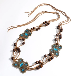 Détail de la chaîne de taille bohème tressée avec papillons en bronze et perles en bois