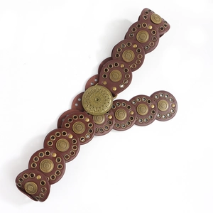 Detail of bohemian leather belt with large embossed bronze buckle and rivet studs