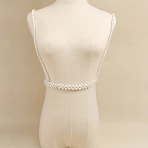Detail van de dubbele rij witte parels op een minimalistische schouder- en tailleketting