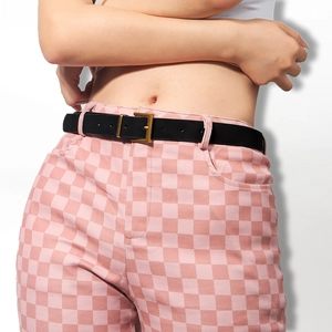 Close-up of minimalist black leather belt with golden square buckle on plaid trousers