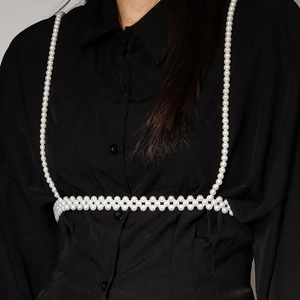 Detail van elegante parel lichaamsketting met schouderbanden over een zwart shirt