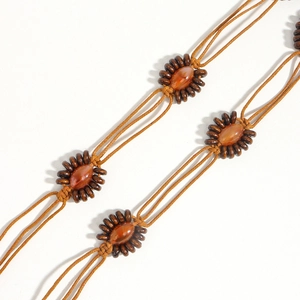 Détail de la chaîne de taille bohème tressée avec perles ambre et accents en bois