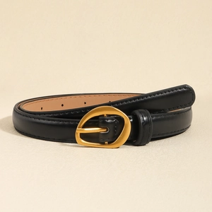 Detail view of a black slim leather belt with a matte gold oval buckle on a beige background