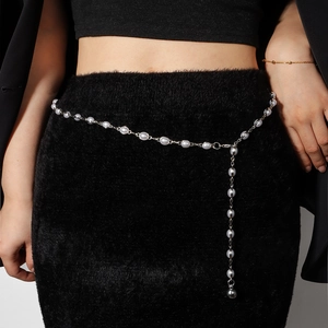 Dettaglio dell'elegante catena in vita con perle e maglie d'argento su abito nero