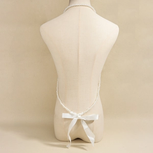 Dettaglio posteriore della catena per il corpo in perle con elegante fiocco in raso bianco
