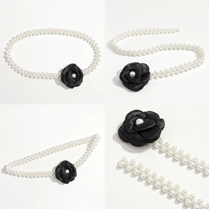 Detailed view of the triple-row pearl waist chain with a black camellia floral buckle