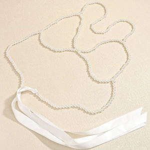 Elegante catena per il corpo multistrato con perle bianche e nastri di seta su fondo beige