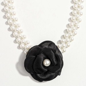 Detail of elegant double-row pearl chain belt with a black camellia floral decorative buckle